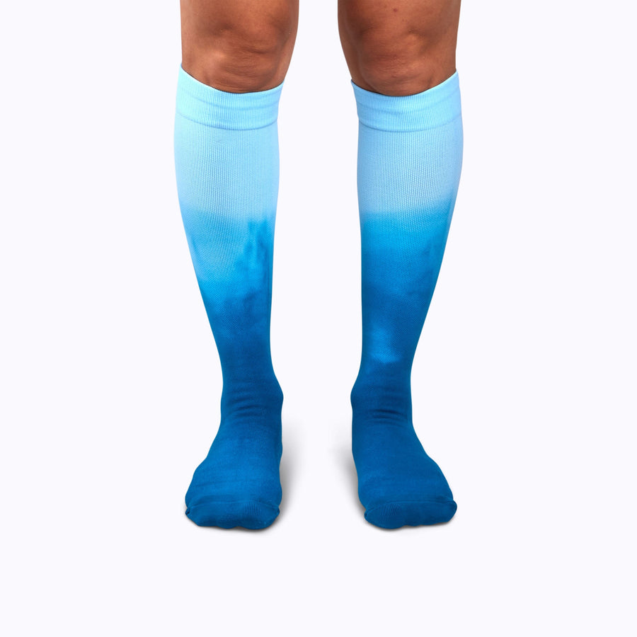 Front view of a pair of legs wearing knee-high compression socks in teal ombre