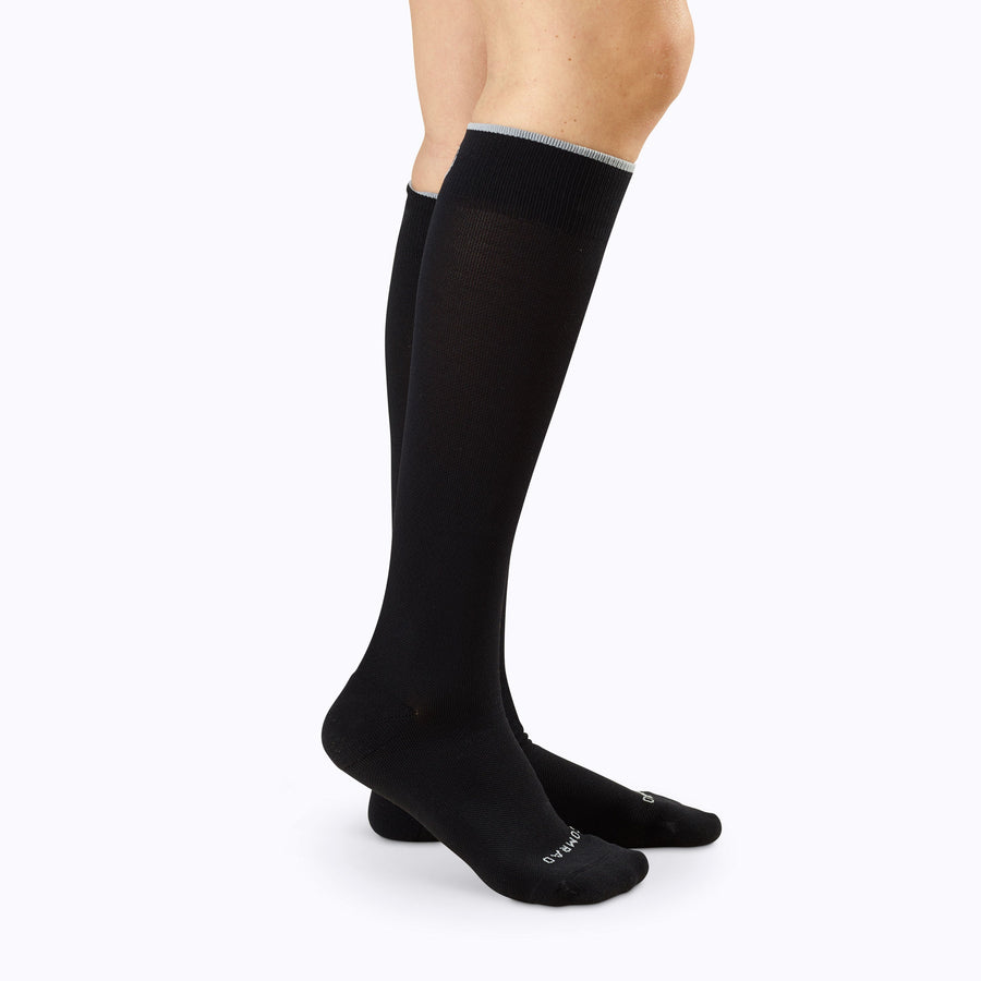 Side view of legs wearing knee high compression socks in solid black