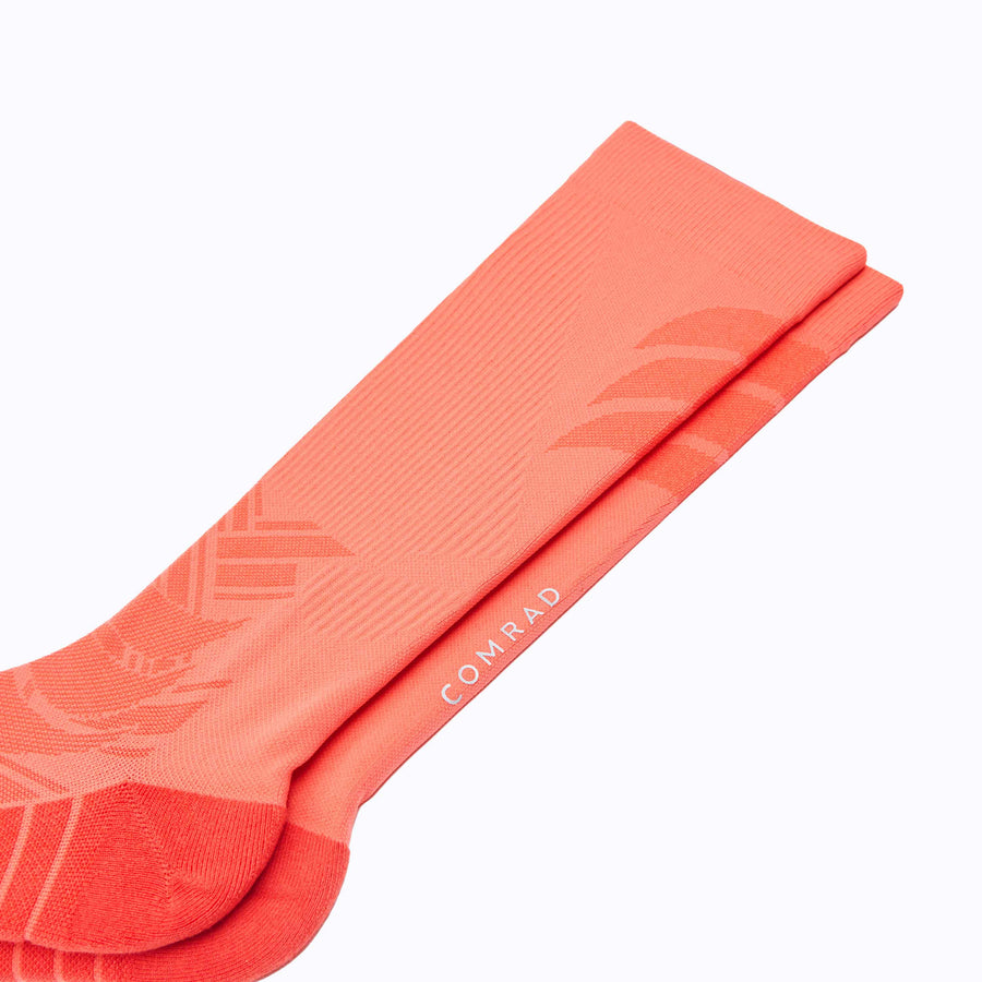 Close up view of an athletic Knee high  performance blend socks coral solid