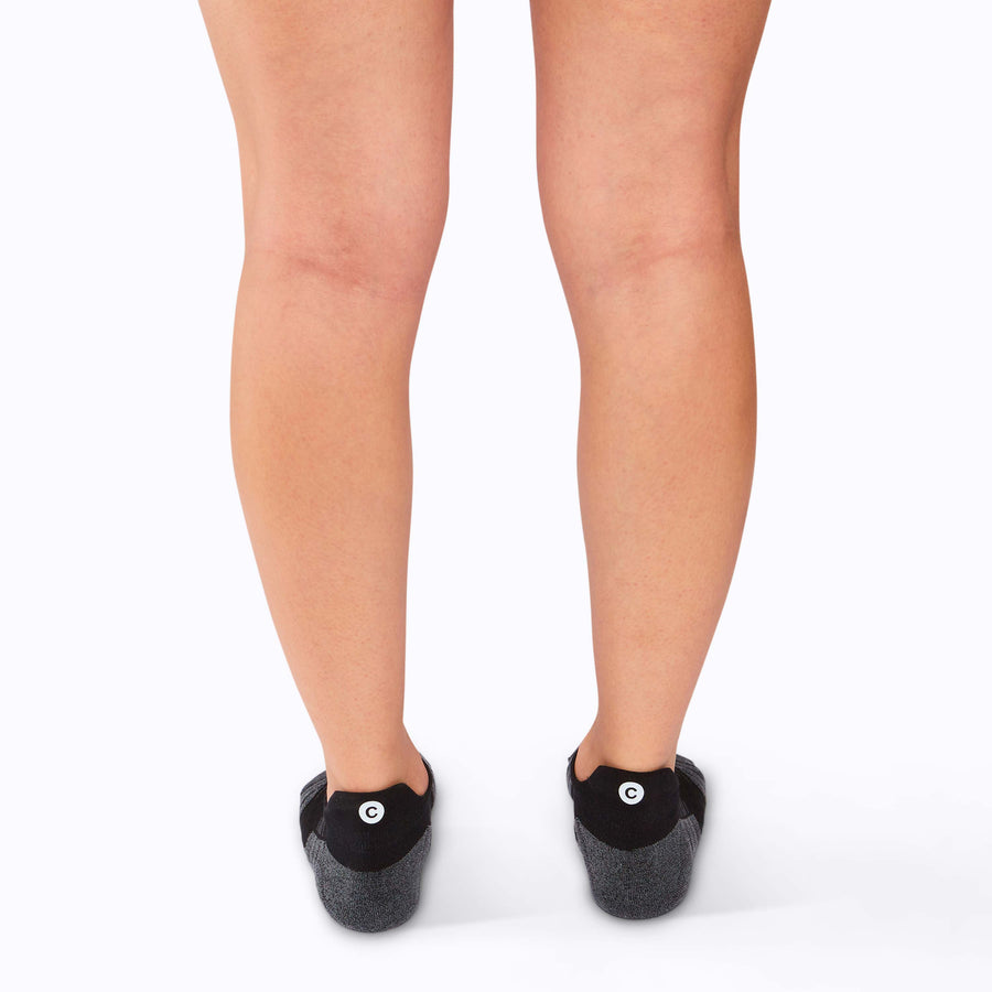 Back view of  feet wearing an athletic tab ankle socks black solid