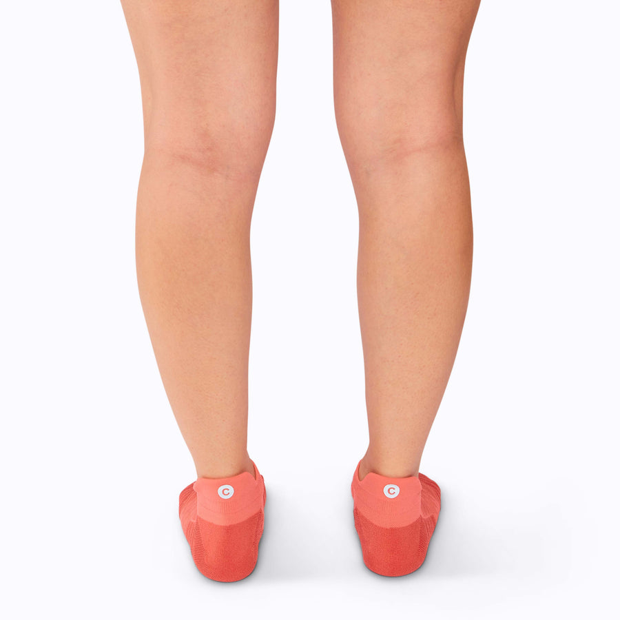 Back view of feet wearing an athletic tab running socks coral solid