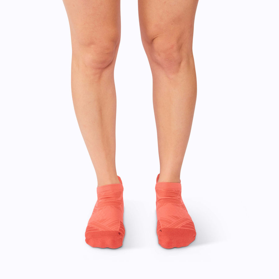 A pair of feet wearing an athletic tab running socks tech coral solid