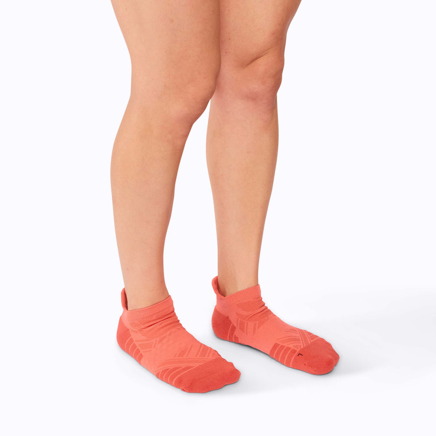 Side view of feet wearing an athletic tab running socks coral solid