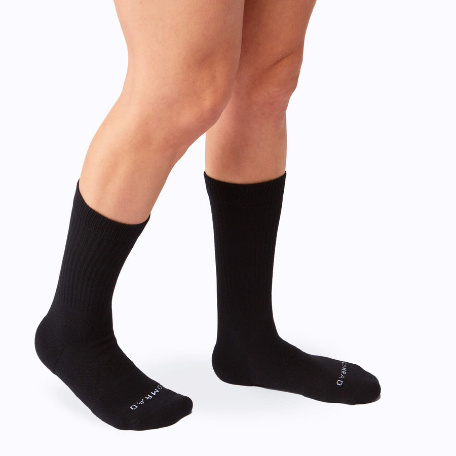 Side view of legs wearing the combed cotton crew socks in black solid