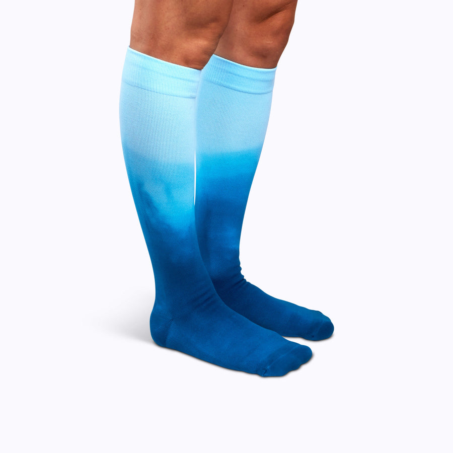 Side view of a pair of legs wearing knee-high compression socks in teal ombre