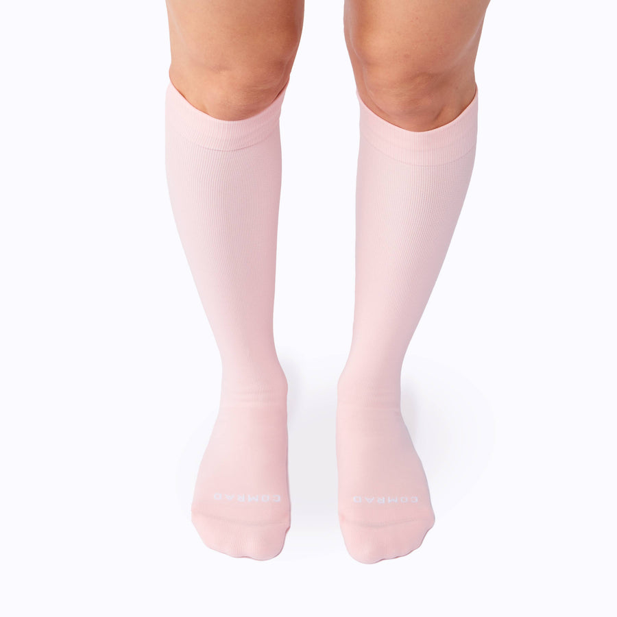 Front view of legs wearing a pair of nylon knee high compression socks in rose solid