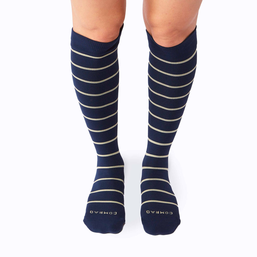 Front view of legs wearing a pair of knee high compression socks in navy-sand stripes