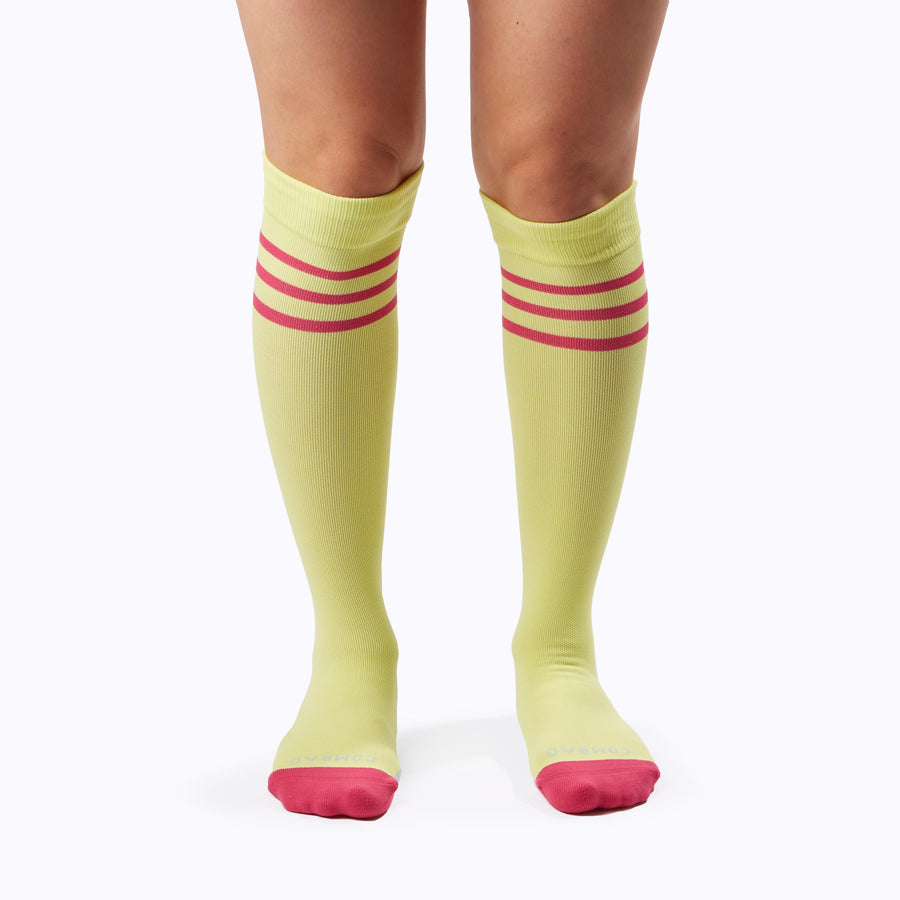 Front view of a pair of legs wearing varstity stripes knee high compression socks in pear and berry