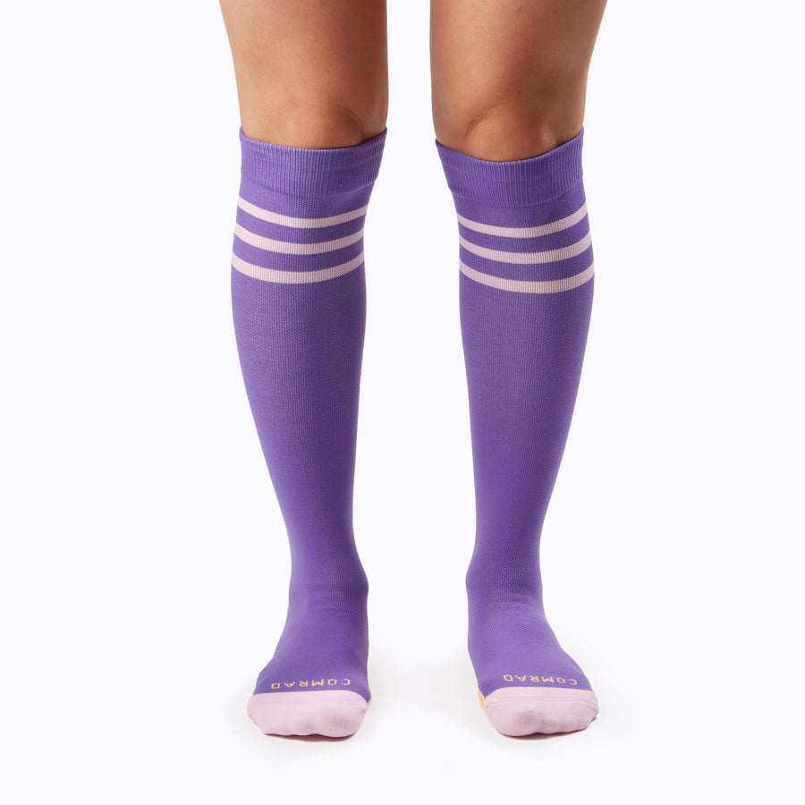 Front view of a pair of legs wearing varstity stripes knee high compression socks in violet and bubblegum