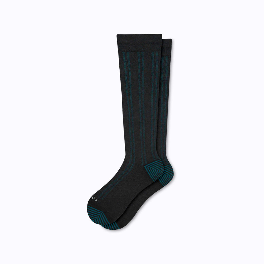 A pair of merino knee high compression socks in black-botanical tencel stripes